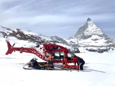 Rescue crew and ski patroller prepare patient lying in rescue bag for transport to hospital. The Matterhorn in the background. 